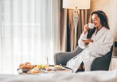 Woman eating breakfast in the hotel room. Room service breakfast in hotel room.