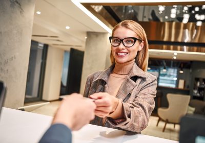 Young woman in hotel check in at reception or front office being given key card